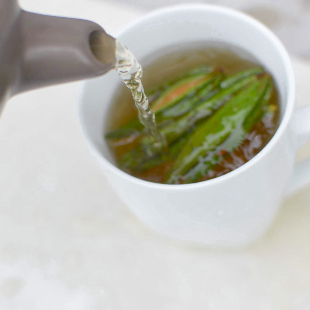Théière verse eau chaude sur les feuilles de thé du Labrador